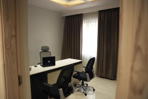 a room with a desk with two chairs and a laptop at TR Hotels in Ambāla