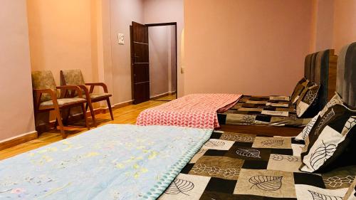 a room with two beds and a table and chairs at shree shivnandan homestay in Ujjain