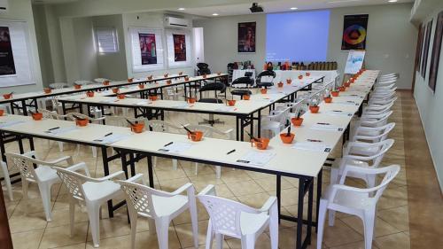 a large room with long tables and white chairs at BM Hotel in São Sebastião do Paraíso