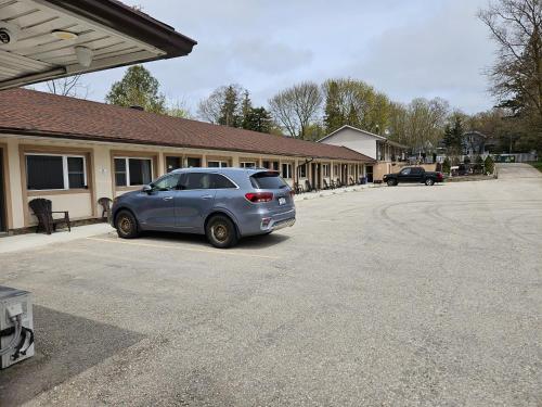 a car parked in a parking lot in front of a building at Forest Plaza Motel in Mount Forest