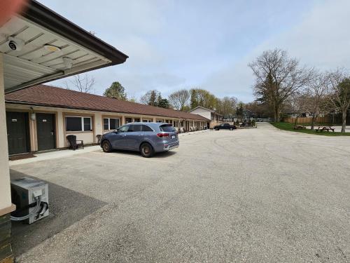 a car parked in a parking lot in front of a building at Forest Plaza Motel in Mount Forest