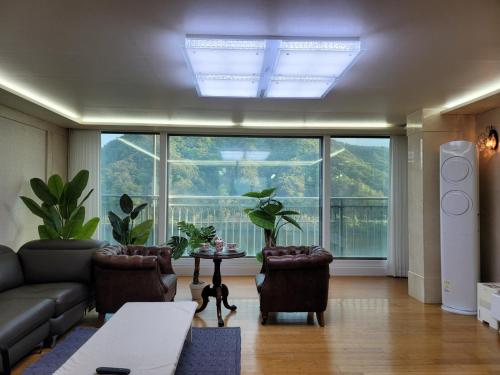 a living room with a couch and a table and large windows at 최고의뷰 강변리조트 in Chuncheon