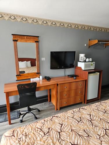 a desk with a television and a mirror in a room at Forest Plaza Motel in Mount Forest