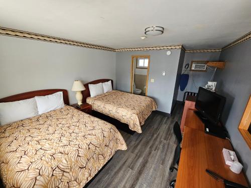 a hotel room with two beds and a television at Forest Plaza Motel in Mount Forest