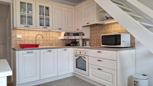 a kitchen with white cabinets and a microwave at Cosy Nest in Bovec