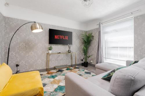 a living room with a couch and a tv on the wall at Boutique 3bd Opposite Etihad & Coop - Free Parking - Pool Table in Manchester