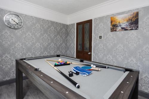 a pool table in a room with a clock at Boutique 3bd Opposite Etihad & Coop - Free Parking - Pool Table in Manchester