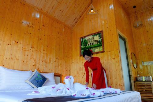 a woman standing next to a bed in a room at Bungalow Ven Sông in Ấp Phú Hòa (2)
