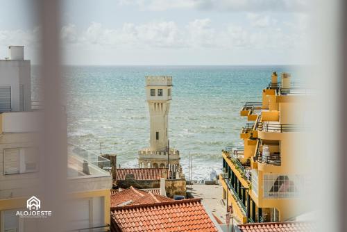 a lighthouse in the middle of a city with the ocean at Casa do Terraço - Center of Santa Cruz with Sea View in Santa Cruz