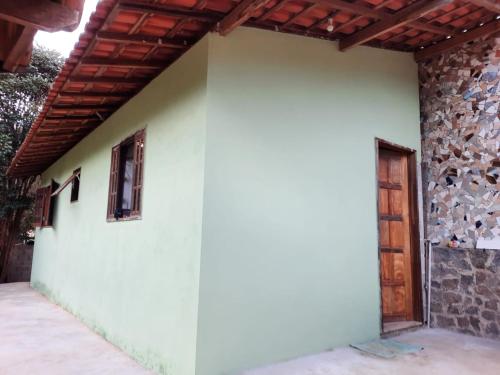 a white wall with a wooden roof and a door at Sítio Jabuticabeira in Santo Antônio do Pinhal