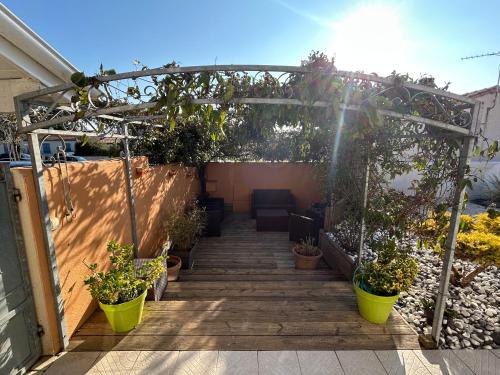 une terrasse avec des plantes en pot et une pergola dans l'établissement Maison dans village cotier, à La Celle-sous-Gouzon