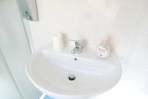 a white bathroom sink with a bottle of soap on it at Case al mare in Salento B12 in Marina di Leuca