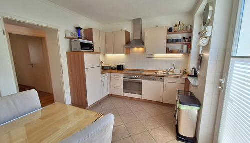 a kitchen with white appliances and a wooden table at Insellicht BRINKMANNHAUS - entspannend groß fast am Strand Sauna Terrasse Grill in Bansin