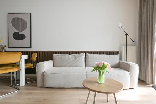 a living room with a couch and a vase of flowers on a table at Apartamenty Florina Q4Apartments in Łeba