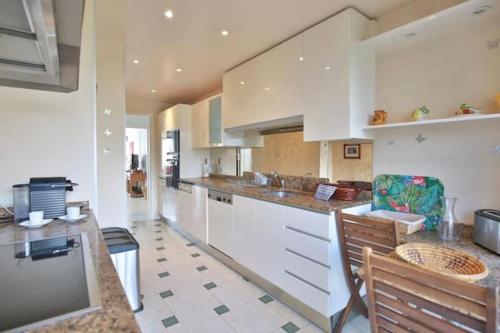 une cuisine avec des armoires blanches et une table et des chaises dans l'établissement 3BDR with SeaViews and Big Terrace, à Antibes