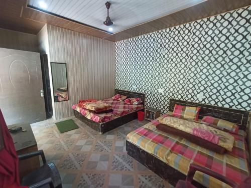 a room with two beds and a mirror in it at Hotel Prabhat & Resturent in Ukhimath