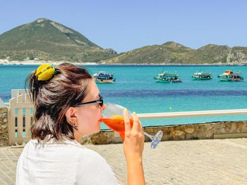 a woman drinking a drink from a wine glass at Hotel Recanto do Atalaia in Arraial do Cabo
