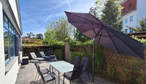 a table and chairs with an umbrella on a patio at Johanna BRINKMANNHAUS -historisch viel Platz fast am Strand Sauna Terrasse Grill in Bansin