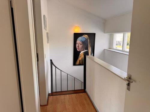 a hallway with a painting of a woman on the wall at Family house next to train and close to Amsterdam and Schiphol in Almere