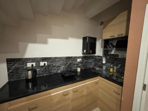 a kitchen with a black counter top and wooden cabinets at Villa 65 - Eco Village - No Alcohol Zone in Yelagiri