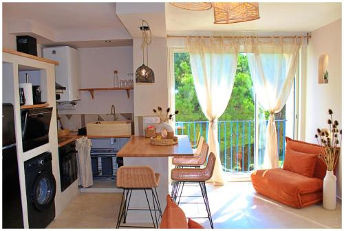 Il comprend une cuisine et un salon avec une table et une grande fenêtre. dans l'établissement Appartement standing avec spa, terrasse & calme absolu, Entre mer et lac, La Grande Motte, à La Grande Motte