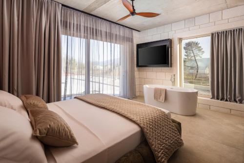 a bedroom with a bed and a tv and a tub at NEW! Contemporary Villa Fantazija – A Luxurious Retreat in Dicmo in Dicmo