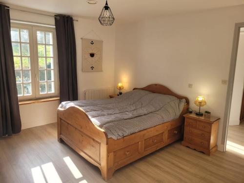 une chambre avec un lit en bois et deux tables de nuit dans l'établissement Maison de campagne normande et accueil chevaux, à Percy