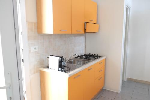 a kitchen with yellow cabinets and a stove top oven at Case al mare in Salento - bilocale B8 in Marina di Leuca