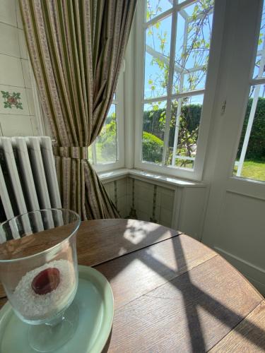 a table with a vase on a plate next to a window at Walden in Lo-Reninge