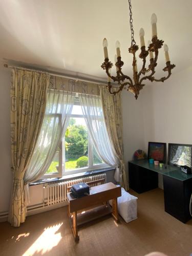 a living room with a chandelier and a window at Walden in Lo-Reninge