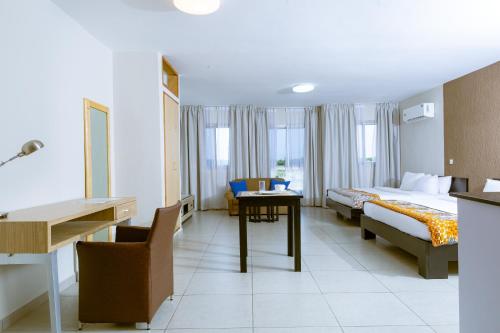a hotel room with two beds and a desk and a table at Résidences Les Hauts de l'Indenié in Abidjan
