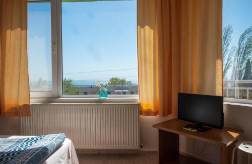 a room with a bed and a television and a window at Family Hotel Perla in Golden Sands
