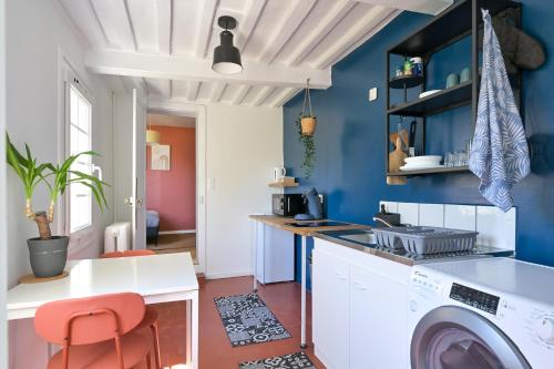 - une buanderie avec des murs bleus et un lave-linge/sèche-linge dans l'établissement Aliénor, à Montivilliers