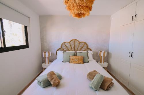een slaapkamer met een groot wit bed met kussens bij Playa y Palmera in Corralejo