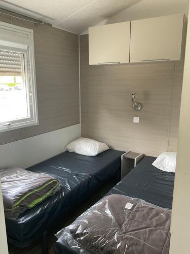 乐巴凯尔斯Azur Premium Climatisé 4 étoiles au camping la presqu'île du Barcarés vue imprenable的一间带窗户的小房间里有两张床