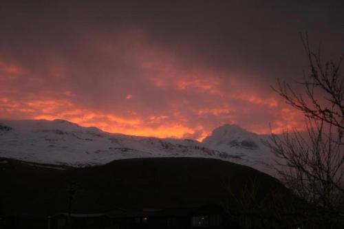 a sunset over a snow covered mountain with a red sky at The Writer´s Nest in Grundarfjordur
