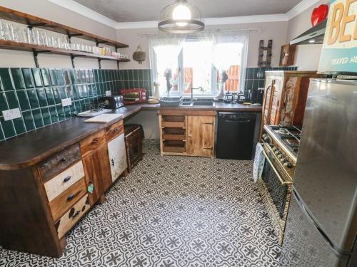 a kitchen with wooden cabinets and a tile floor at Sailaway in Carbis Bay