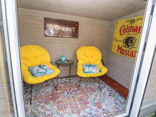 two yellow chairs in a small room with a table at Sailaway in Carbis Bay