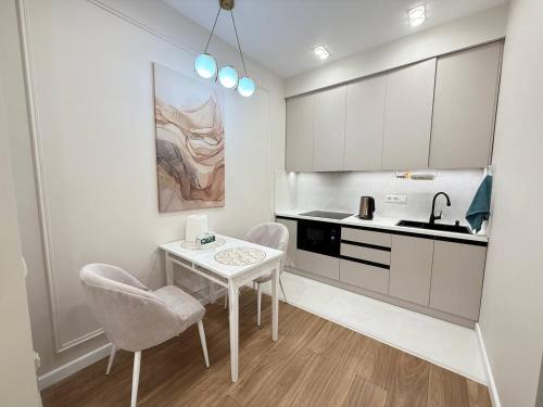 比什凯克SunHouse apartment的厨房配有桌子、两把椅子和水槽