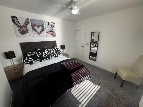 a bedroom with a black and white bed and a chair at Parkview holiday apartments GroundFloor in Skegness