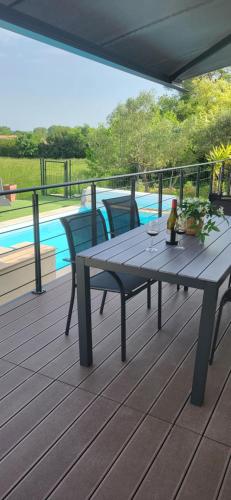 une terrasse en bois avec une table de pique-nique et des chaises à côté d'une piscine dans l'établissement Villa Piscine vue dégagée, à Montaren-et-Saint-Médiers