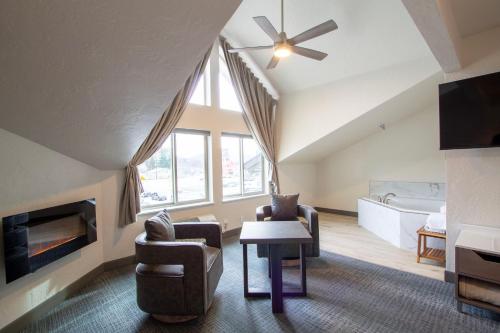 a living room with a ceiling fan and a couch and chairs at Cedar Street Hotel & Suites in Sandpoint