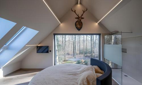 a bedroom with a bed and a large window at Au bout du bois in Jalhay