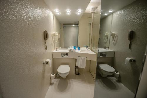 a bathroom with two toilets and a sink and a mirror at Hotel Turquoise All Inclusive in Venus