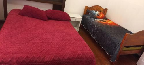 Un dormitorio con una cama roja y una silla. en Alojamiento Yanira, en Valparaíso