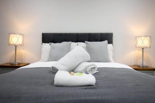 a bedroom with a bed with towels and two lamps at Beautiful 3Bed Flat in Belfast City Centre in Belfast