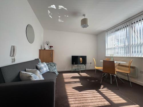 a living room with a couch and a table at Chic Trafford Apartment, Private Underground Parking, Fast Wi-Fi, Self Check-in Anytime, 5 mins to Old Trafford Stadium in Manchester