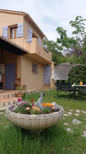un grand bol en pierre avec des fleurs devant une maison dans l'établissement Les Cigales, à Villelaure