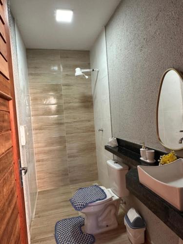a bathroom with a sink and a toilet and a mirror at Aconhego Dourado I Alugue casa com piscina a 17min da praia in Parnaíba