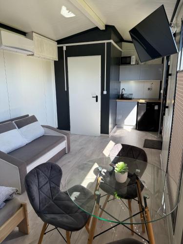 a living room with a glass table and a bed at Domki Kalimera 3 in Jantar